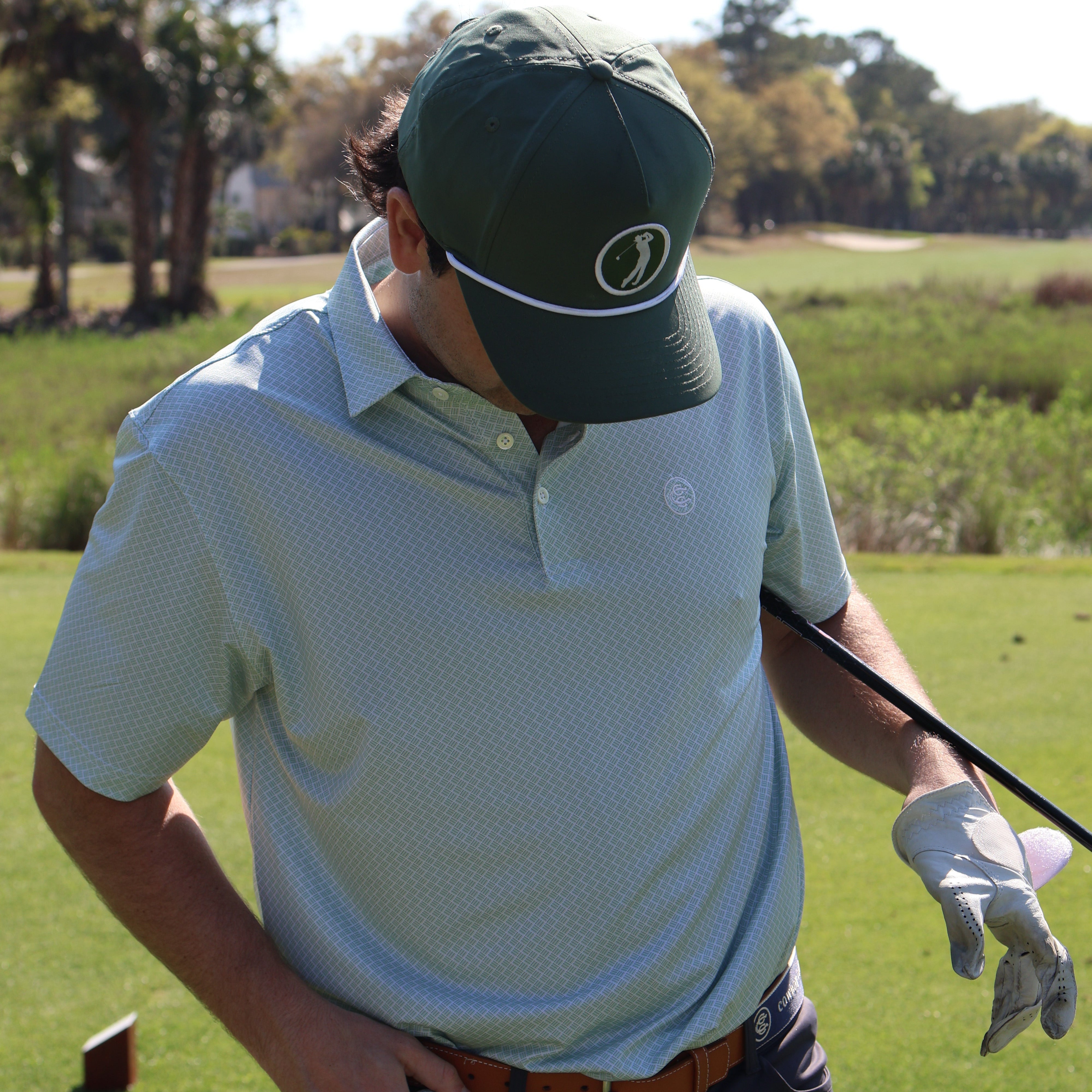Person playing golf on a grassy field with trees in the background